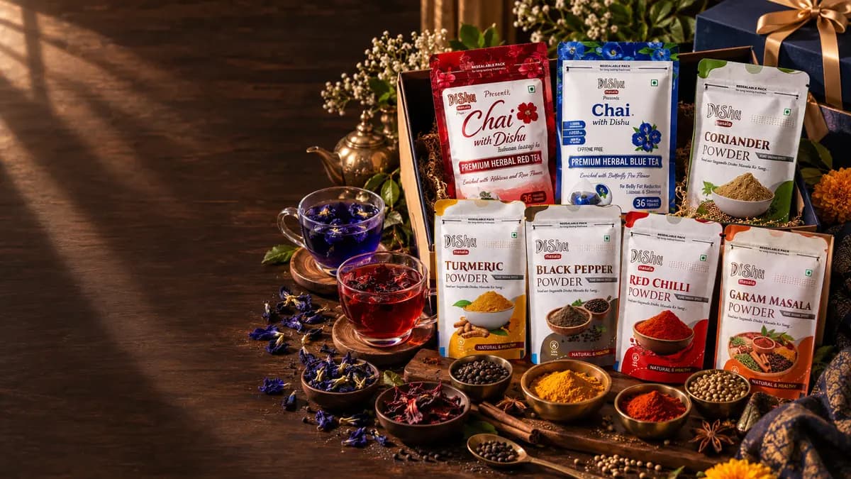 Dishu Masala corporate gifting hamper — Chai with Dishu Premium Herbal Blue Tea and Red Tea, Turmeric, Coriander, Black Pepper, Red Chilli and Garam Masala powders, brewed blue and red tea in glass cups, spices in brass bowls, gift box with gold ribbon on a dark walnut table